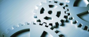 Photograph of three interlocking metallic gears with a smooth, reflective surface, showcasing mechanical components in motion.